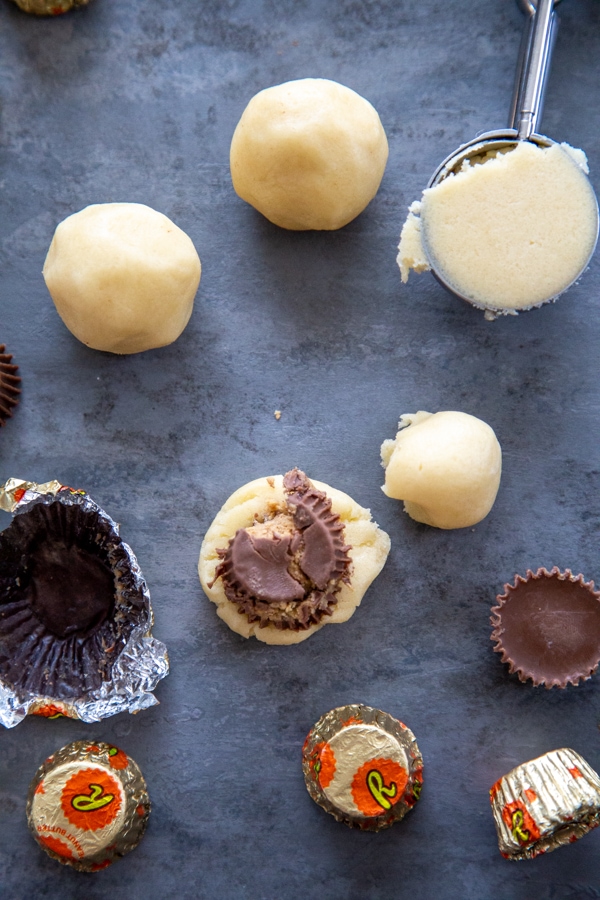 cookie dough balls and dough being stuffed with peanut butter cup.