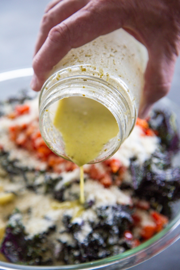 the dressing being poured over the salad.