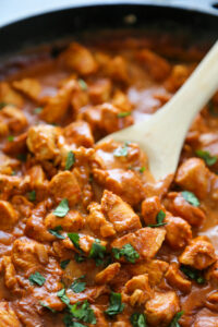 a spoon stirring the butter chicken.