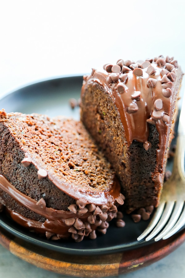 Triple Chocolate Zucchini Cake is just as delicious as it sounds. Chocolate, chocolate, chocolate, and zucchini. This is the best way to eat zucchini. two slices of cake on a plate.