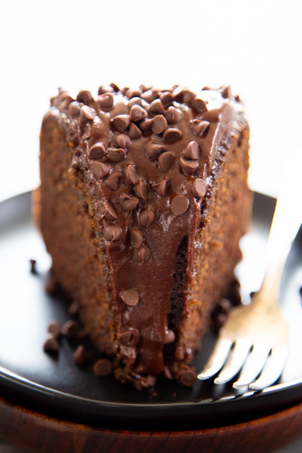 Triple Chocolate Zucchini Cake is just as delicious as it sounds. Chocolate, chocolate, chocolate, and zucchini. This is the best way to eat zucchini. A slice of Triple Chocolate Zucchini Cake on a plate.