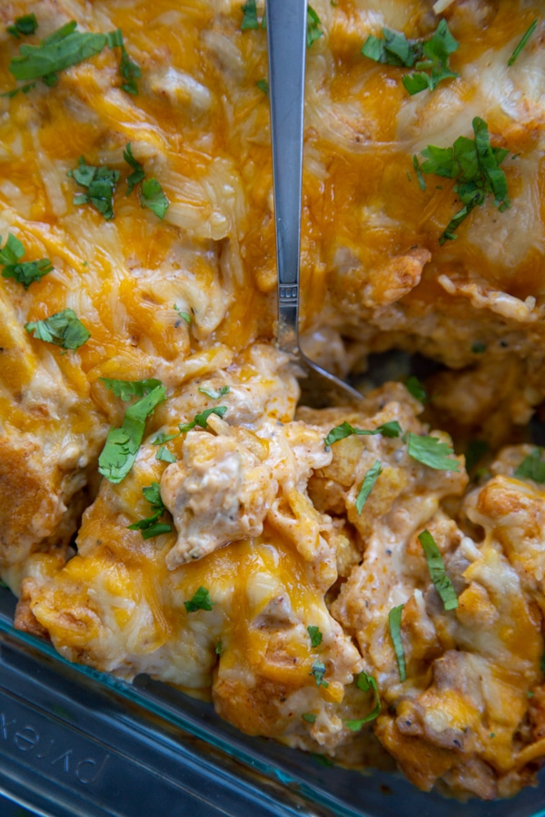 Closeup shot of a large spoon scooping some of the enchilada bake.