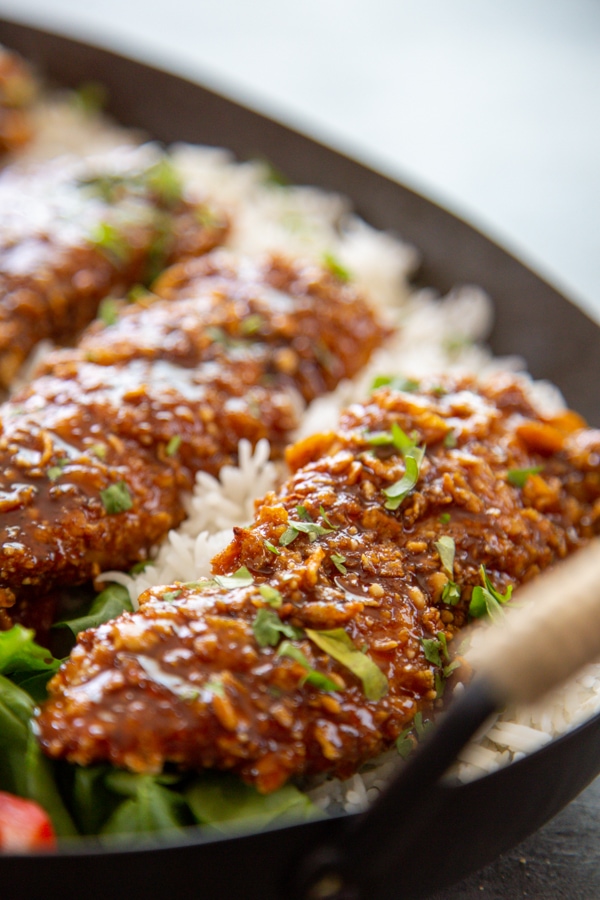 close-up shot of cashew crusted chicken on a plate with rice.