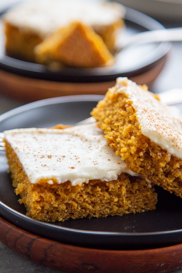 two frosted pumpkin bars on a plate.
