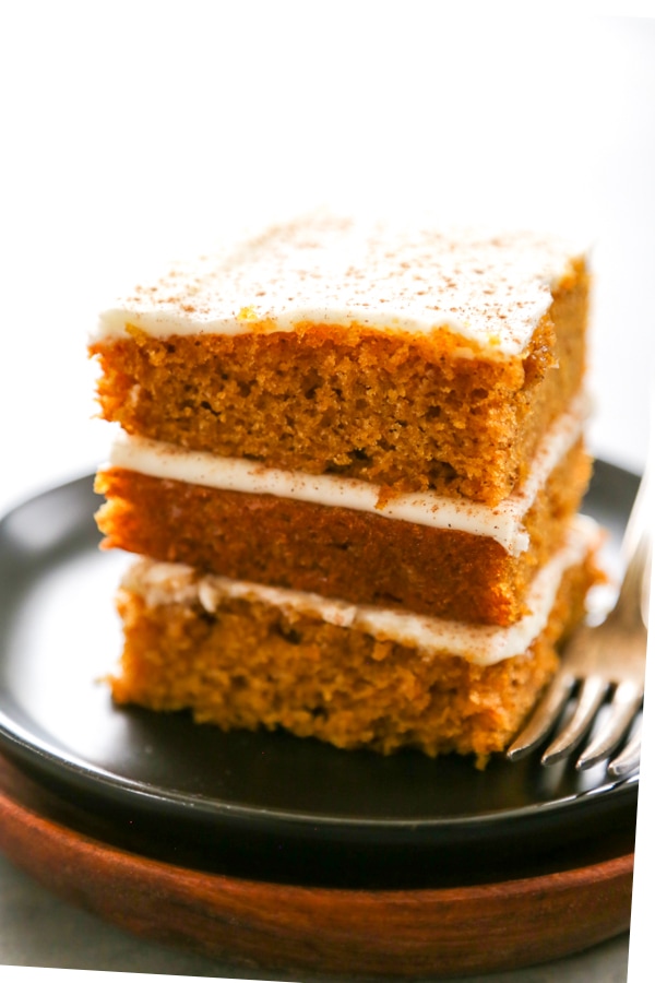 three pumpkin bars stacked on a plate.