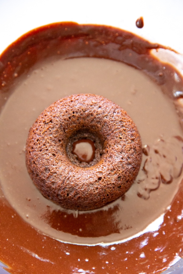 a donut being dipped in the glaze.