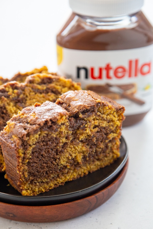 sliced bread on a plate with a jar of Nutella in the background.