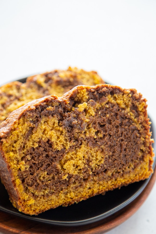 Pumpkin Nutella Swirl Bread takes pumpkin, chocolate, & hazelnut to a new level. Not only is it a beauty to look at, it's moist and full of fall flavors. a slice of bread on a plate.