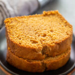 two pieces of pumpkin bread stacked on a plate.
