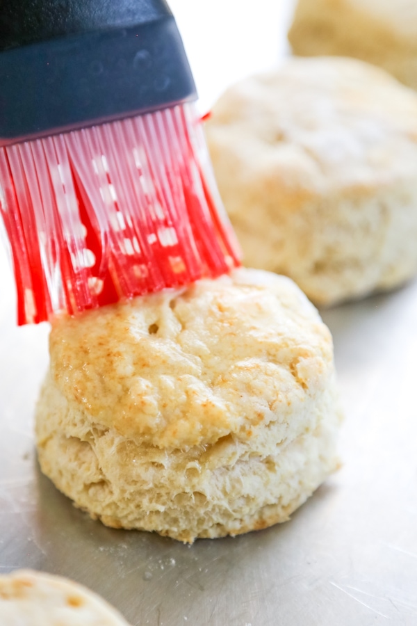 baked biscuit being brushed with butter.
