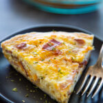 a slice of quiche on a plate with a fork.