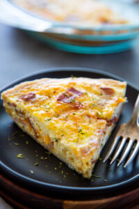a slice of quiche on a plate with a fork.