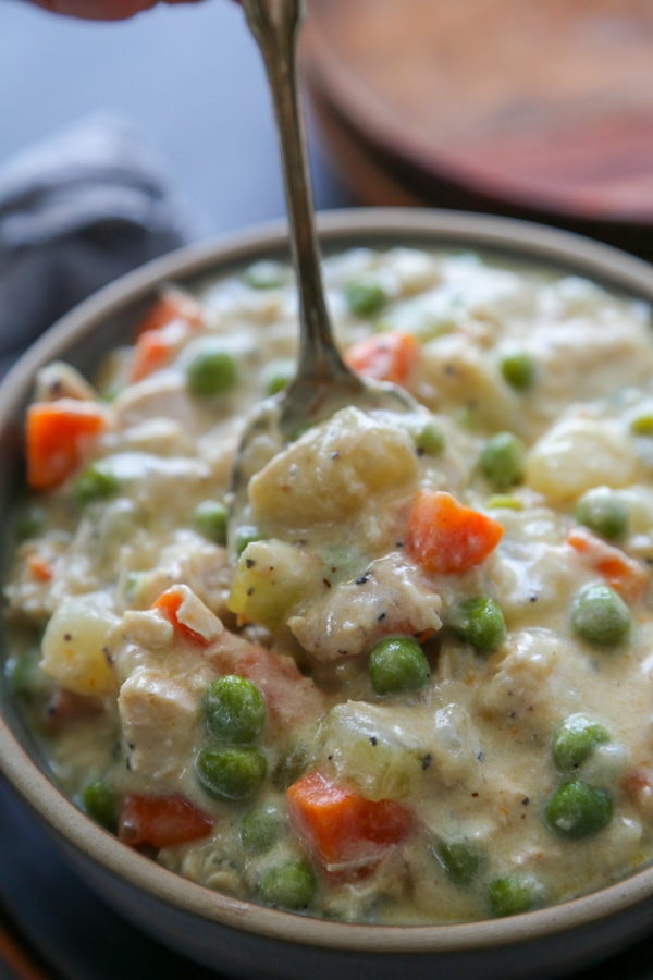 a spoon dipping into a bowl of chicken pot pie soup.