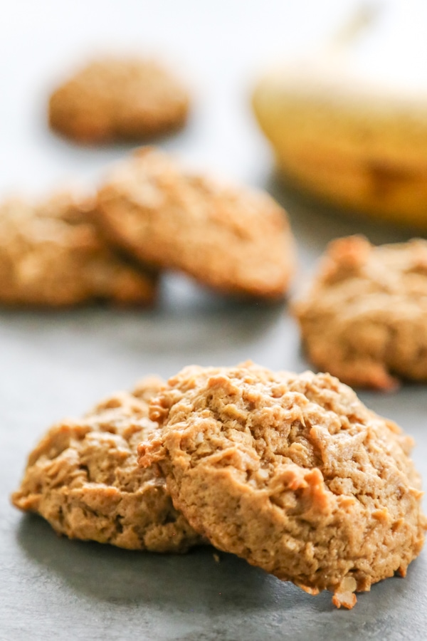 Chewy HEALTHY PEANUT BUTTER BANANA COOKIES are a twist on your peanut butter cookie recipe. Made with no butter and less sugar, they make a great snack! close-up shot of two cookies.