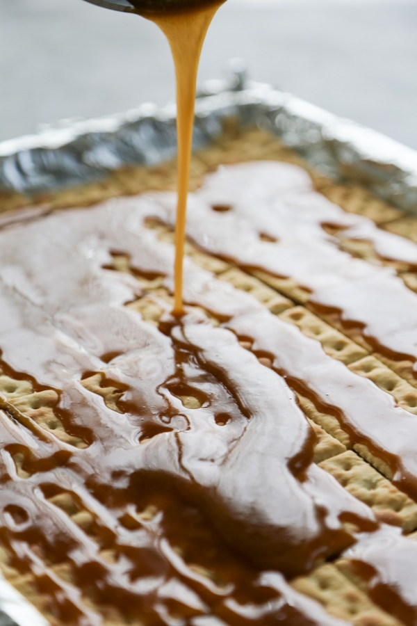 the toffee mixture being poured over the crackers.