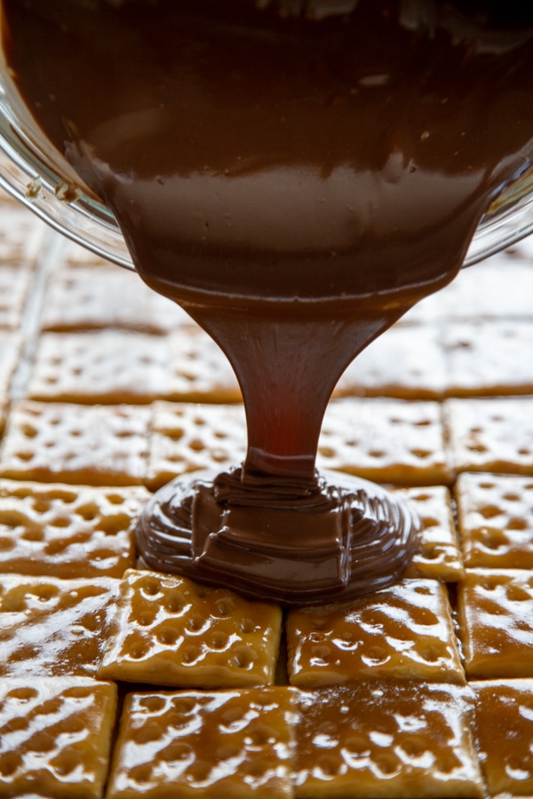 chocolate being poured over the toffee and crackers.