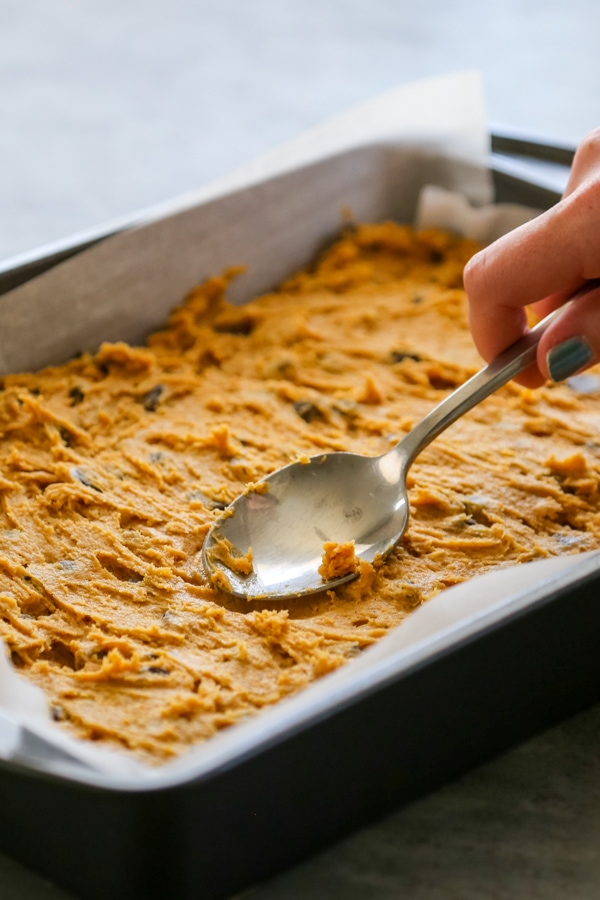the dough being pressed into a baking pan.