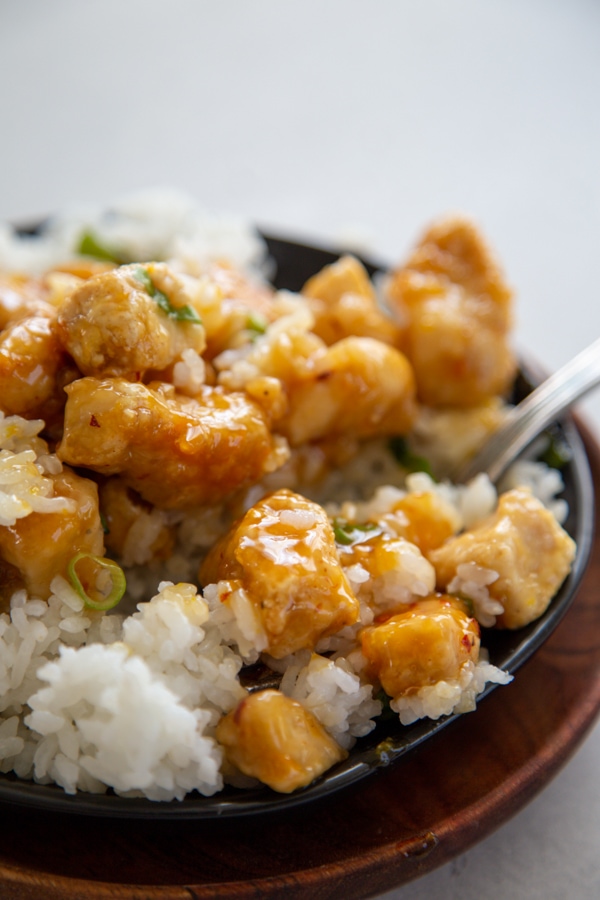 orange chicken and rice on a plate with a fork.
