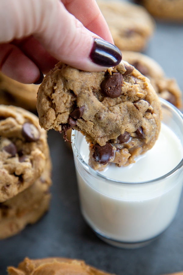 a cookie being dunked into a glass of milk.