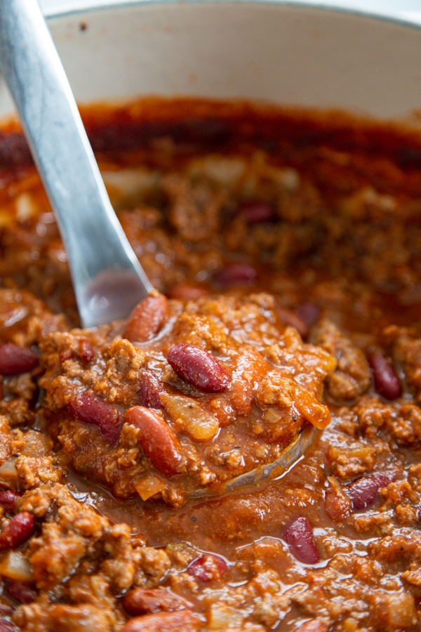 a ladle of chili in a pot.