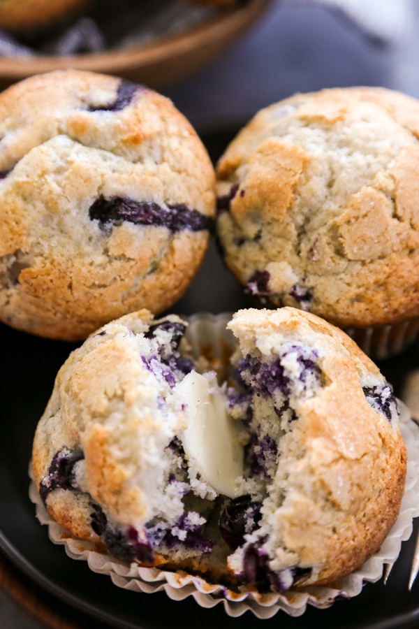 close up of a muffin split in half with butter.