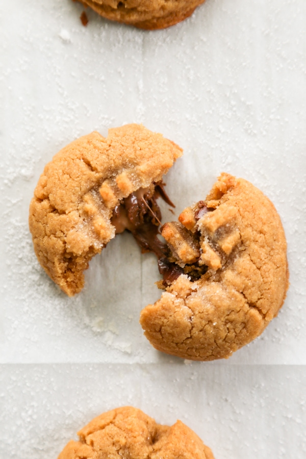 Rolo Stuffed Peanut Butter Cookies are soft and chewy peanut butter cookies with a delicious, melt in your mouth chocolate & caramel center. overhead shot of a cookies broken in half.