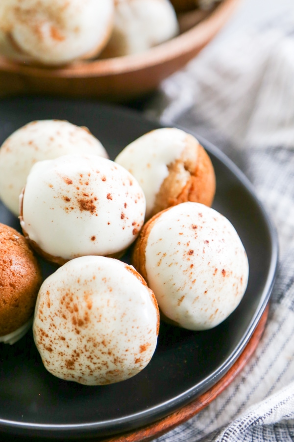 Frosted donut holes piled on a plate.