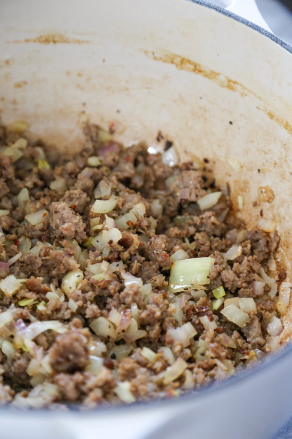 sausage and onions being browned in a pan.