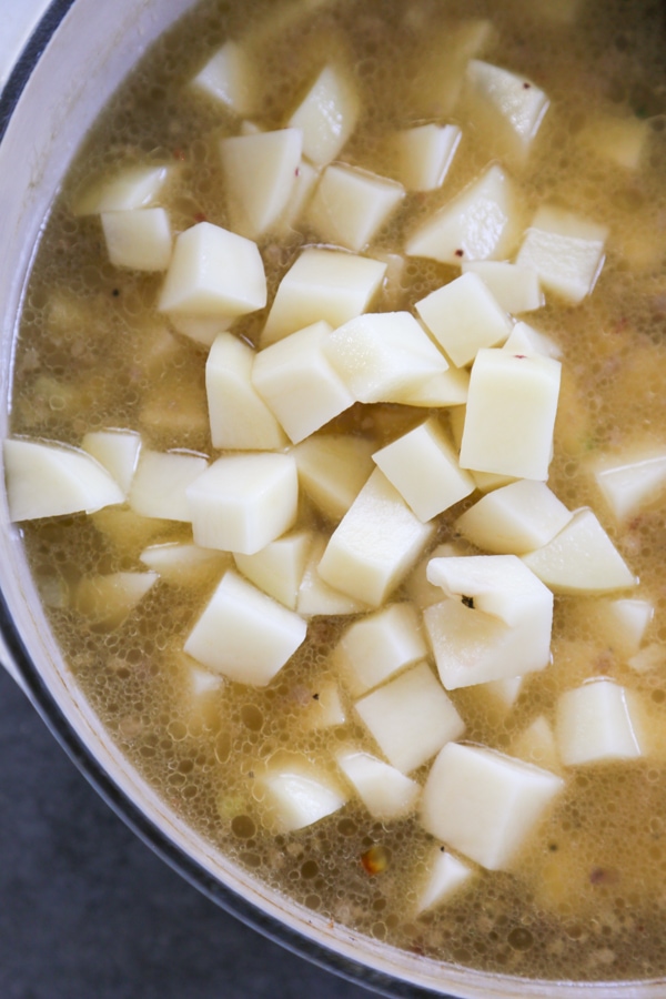 overhead shot of the potatoes added to the soup.
