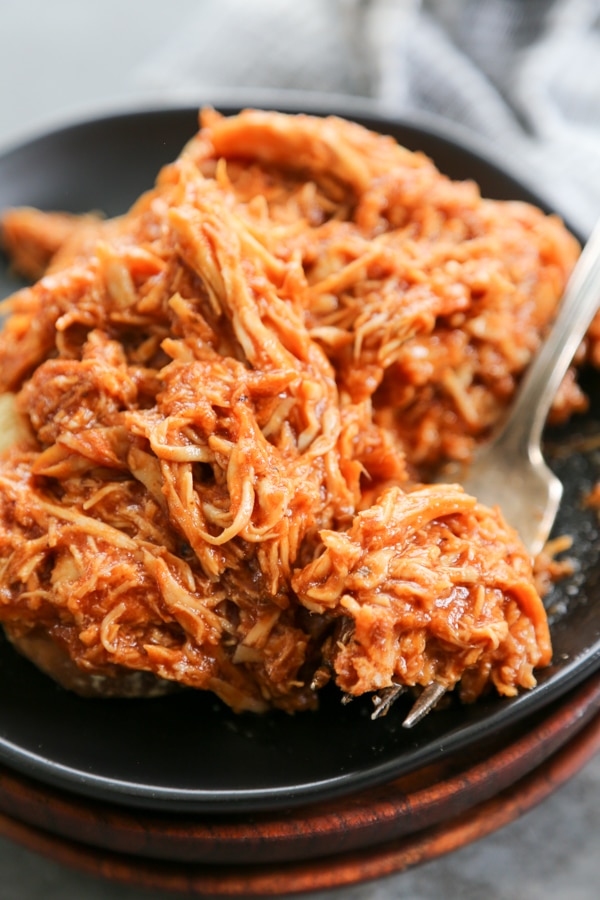 Slow Cooker Chipotle Barbecue Chicken has quickly become our family's favorite barbecue chicken. With the traditional smoky heat from the chipotle seasoning and the sweetness from the barbecue sauce, this creates a mouthwatering combination. close-up shot of the chipotle chicken on a plate with a fork.
