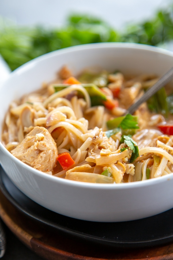a bowl of thai chicken soup with rice noodles.