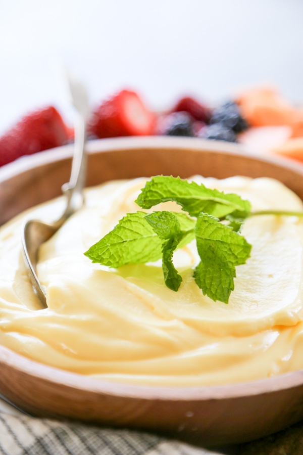 a bowl of sour cream fruit dip garnished with mint.