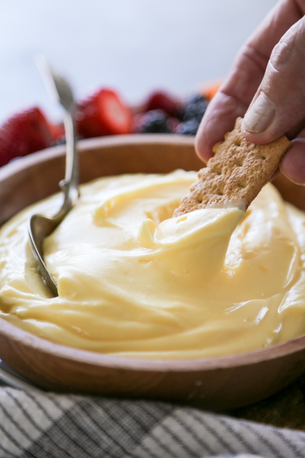 a graham cracker being dipped in a bowl of dip