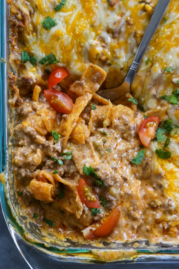 the enchilada casserole in a pan with a serving spoon.
