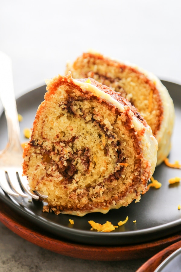 orange swirl cake two slices stacked on a black plate with silver fork