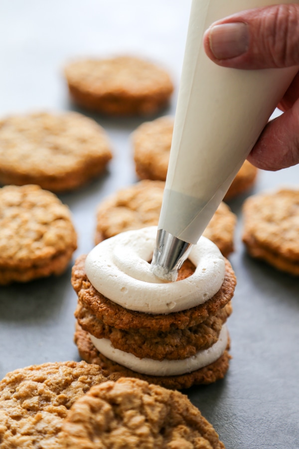 the cream filling being piped onto a cookie.