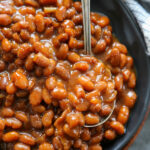 a plate of baked beans with a spoon.