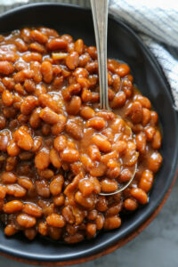 a plate of baked beans with a spoon.