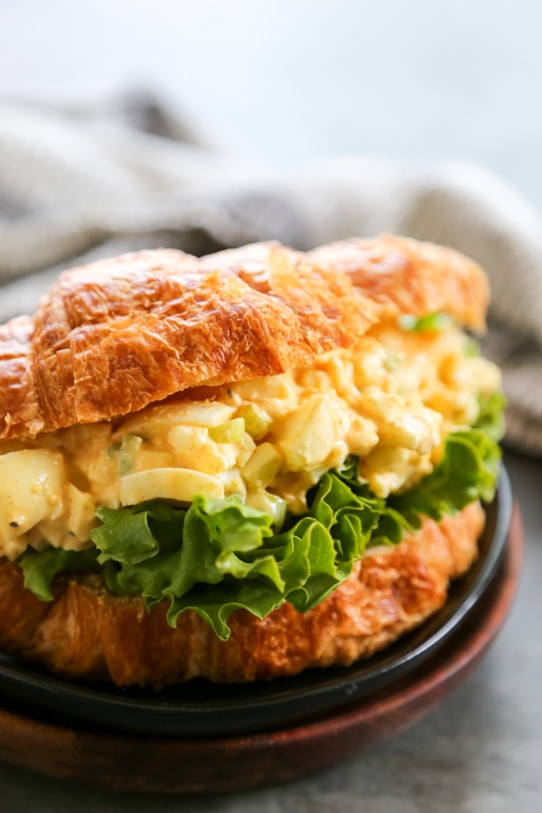 egg salad on a croissant with lettuce.