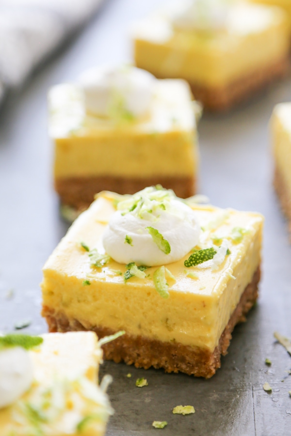 close up shot of a key lime pie bar topped with whipped cream and zest.