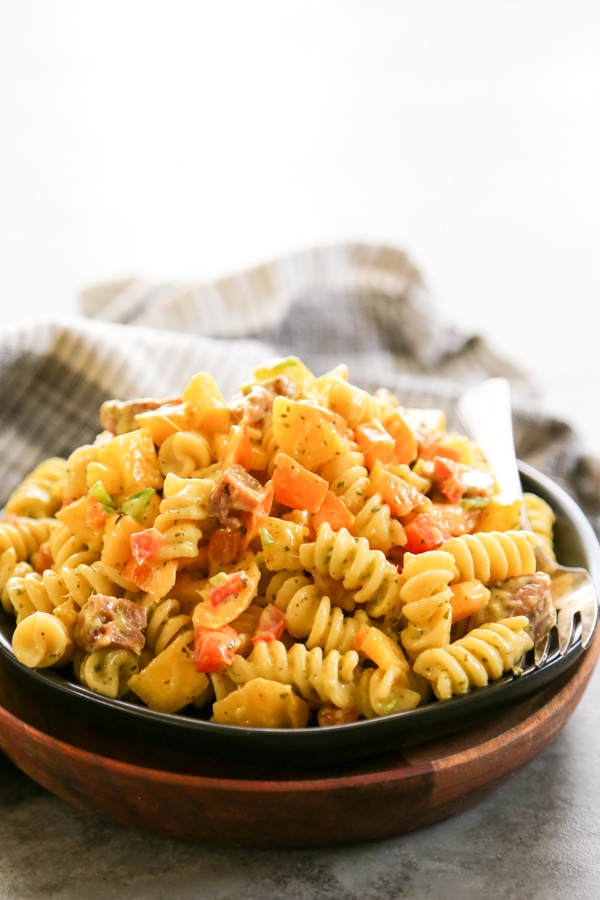 Mango Pasta Salad is a sweet and mildly spicy pasta salad made with fresh mangoes, peppers, sausage, and drizzled with a citrus vinaigrette. a plate of mango pasta salad salad