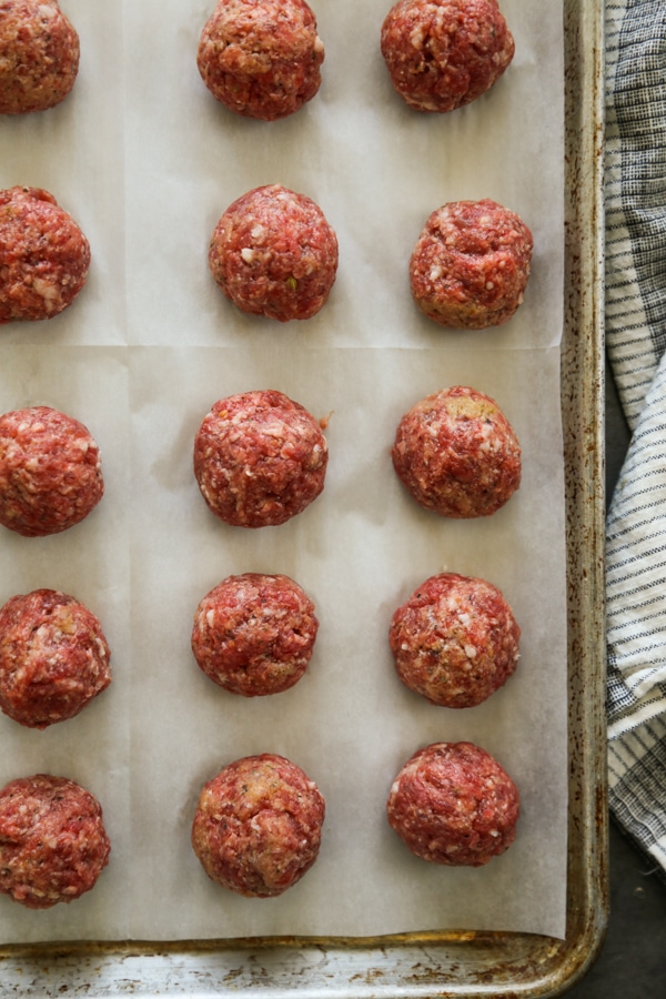 overhead shot of meatballs on a sheet pan ready to be baked.