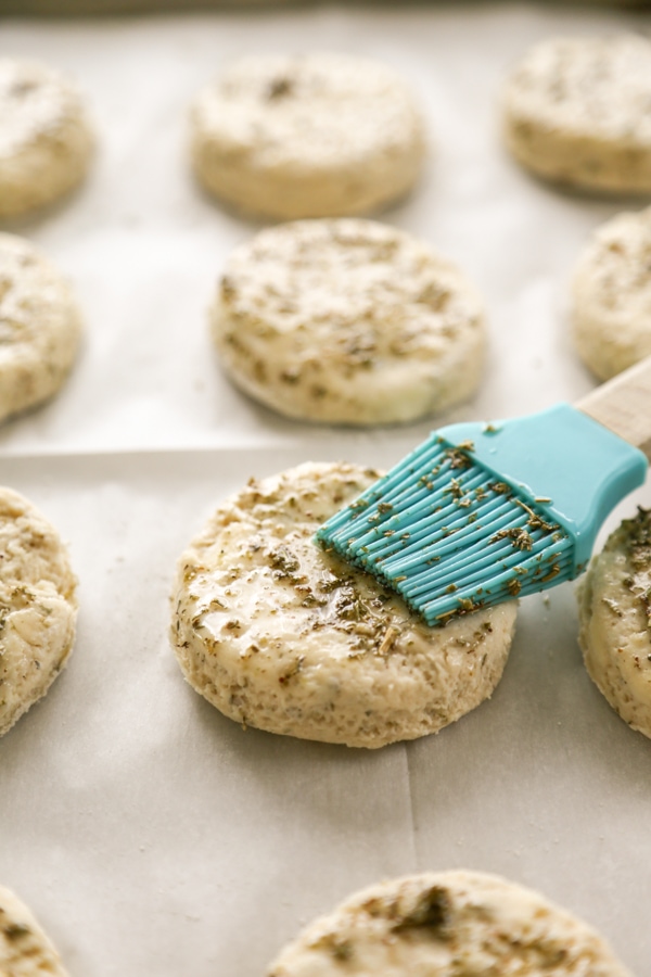 the raw biscuits being brushed with herbs.