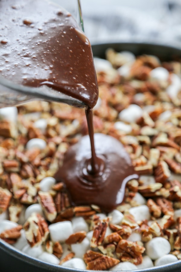 the chocolate sauce being poured over the cheesecake.