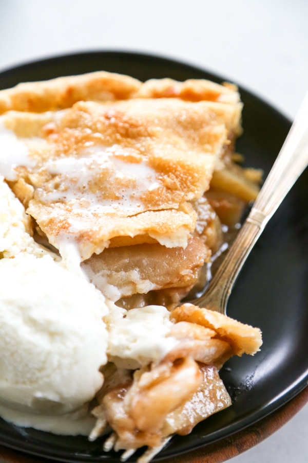 apple pie with ice cream and fork with a bite taken out of the pie