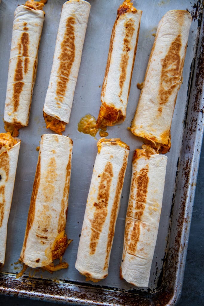 overhead shot baked taquitos on baking sheet