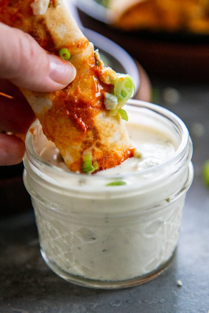 taquito being dipped in dressing