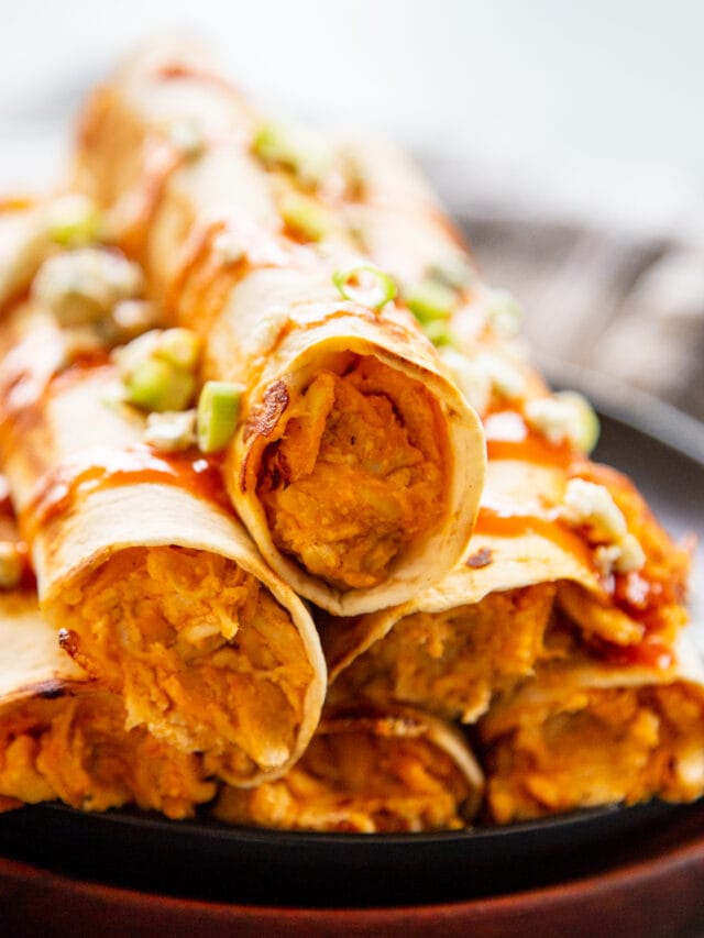 close up shot taquitos stacked on plate