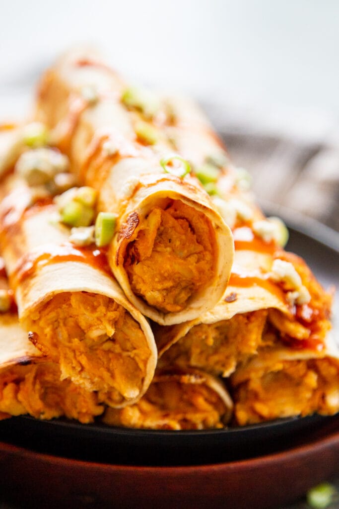 close up shot taquitos stacked on plate
