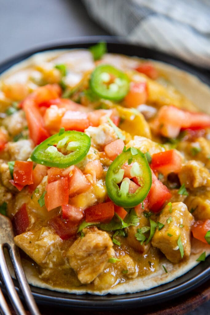 chicken chile verde on plate with tortilla and fork